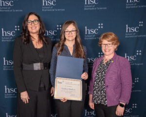 school of biomedical science awards with Lindsey Hudson standing between two SBS faculty with her award