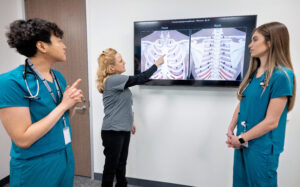 nursing professor showing two students a chest x ray.